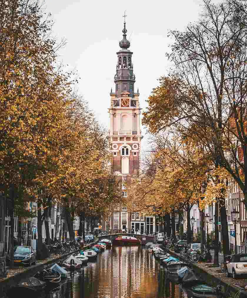 Westerkerk Church in Amsterdam with a view of the canal and the medieval clock tower amongst the trees