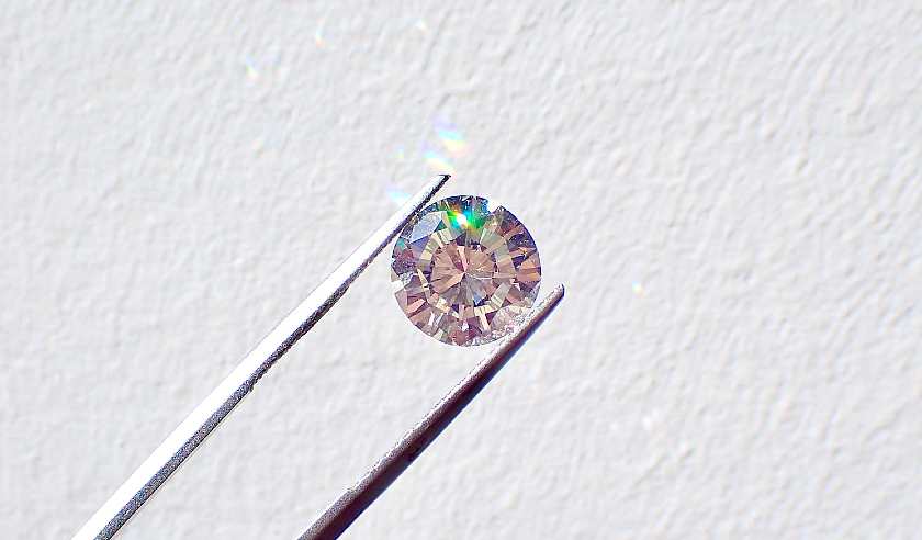 Diamond up close in between some tweezers 