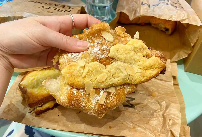 Hand holding an almond croissant at Land and Monkeys in Paris