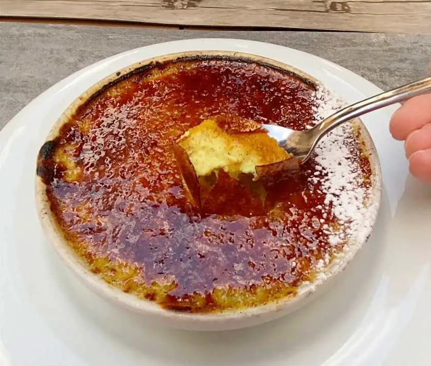 Spoon pulling vegan custard through a caramelised topping Crème Brûlée dessert