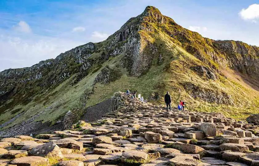 Stone steps at the Giant's Causeway with a green cliff face and people in the background 