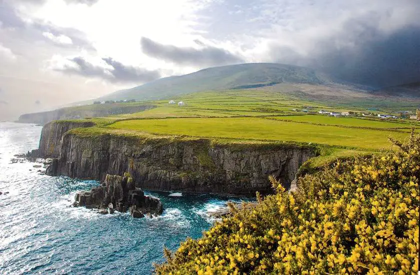 Green cliffs and blue ocean with dark clouds in the background in Northern Ireland
