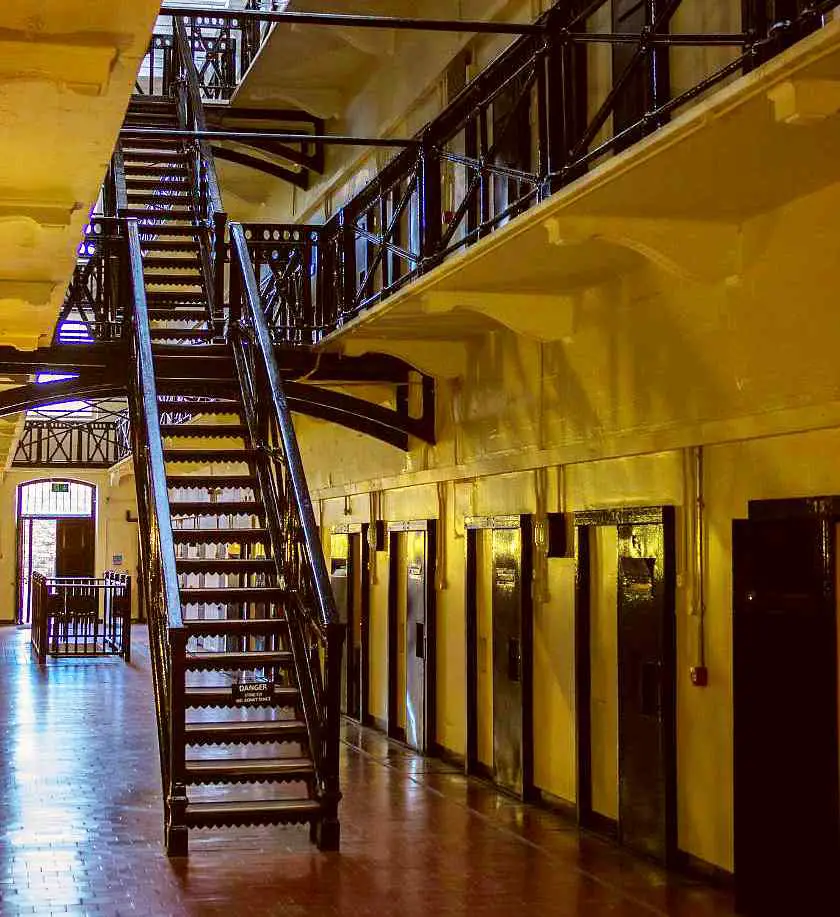 Inside Crumlin Road Gaol's main corridor with rows of black victorian jail cell doors open