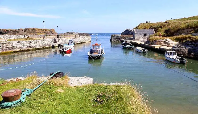 Ballintoy Harbour on a sunny day with small boats moored on the edge of the walls which is one of the Game of Thrones locations in Northern Ireland