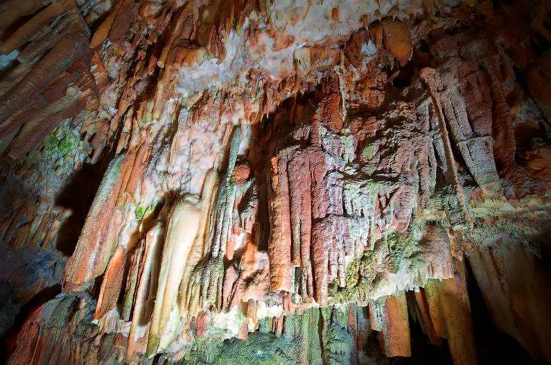 Orange and spiky rock formations on the ceiling of Drogarati Cave, lit up with bright light