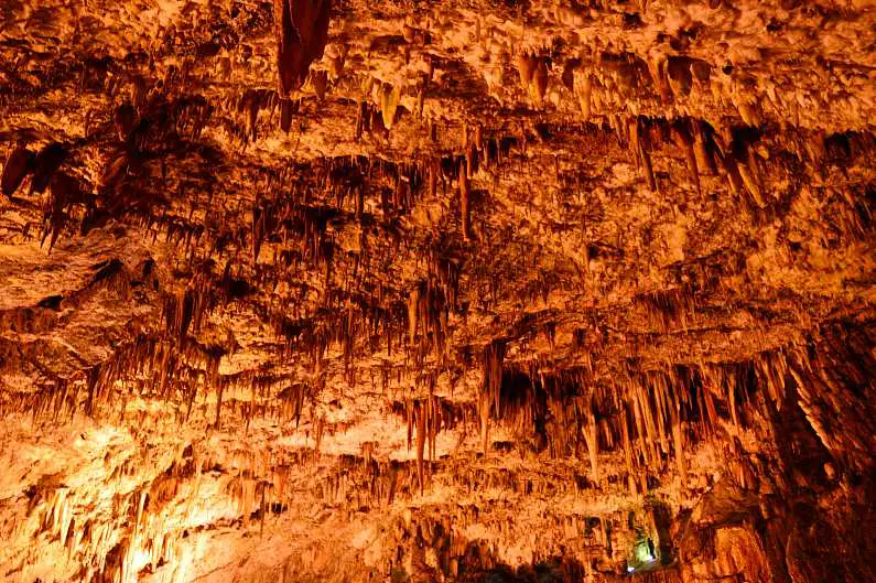 Stalactites on the ceiling of Drogarati Cave, lit up with orange lights