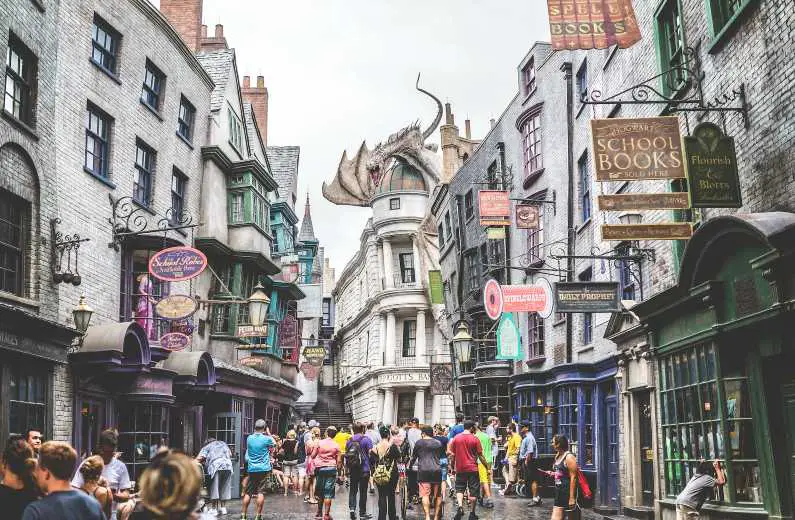 Diagon Alley in Universal Studios with Harry Potter themed shops either side and the dragon on top of Gringotts Bank 