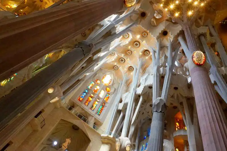 Ceiling of Sagrada Familia with stained glass windows and columns