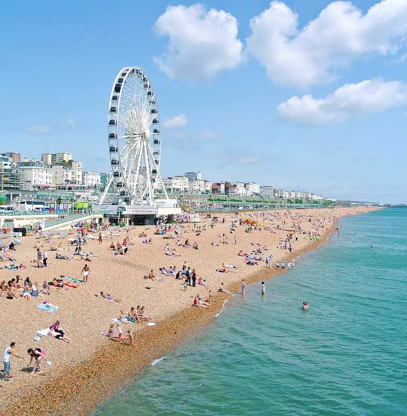 Brighton seafront and beach with a ferris wheel in the background on a sunny day