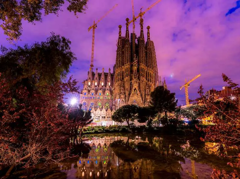 Sagrada Familia at dusk with a purple sky in the background amongst the trees