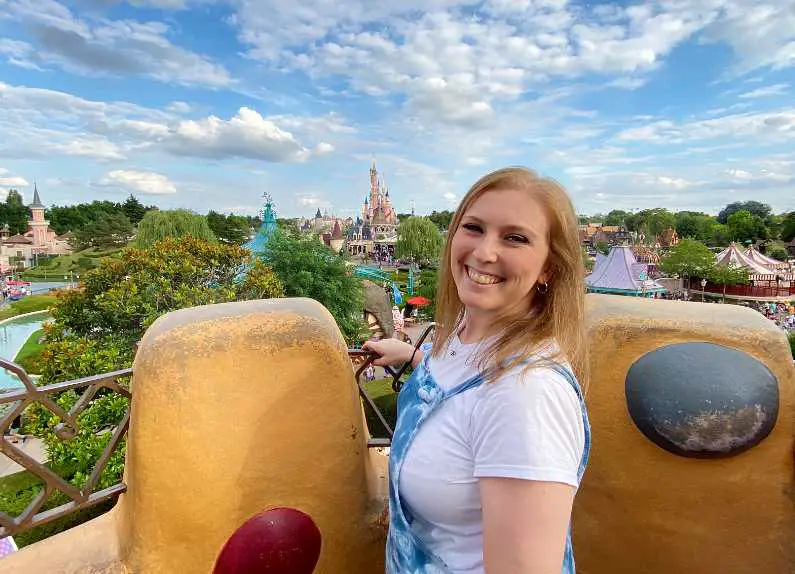 Mel at the top of the Queen of Hearts castle in Princess Land with Sleeping Beauty's Castle in the background