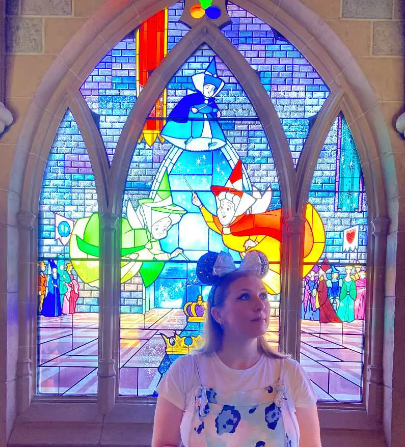 Mel looking at the stained glass windows wearing Minnie Mouse ears in Sleeping Beauty's castle in Disneyland Paris