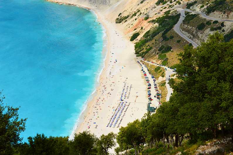 View of Myrtos Beach from the cliff in Kefalonia with bright blue waters people on the beach