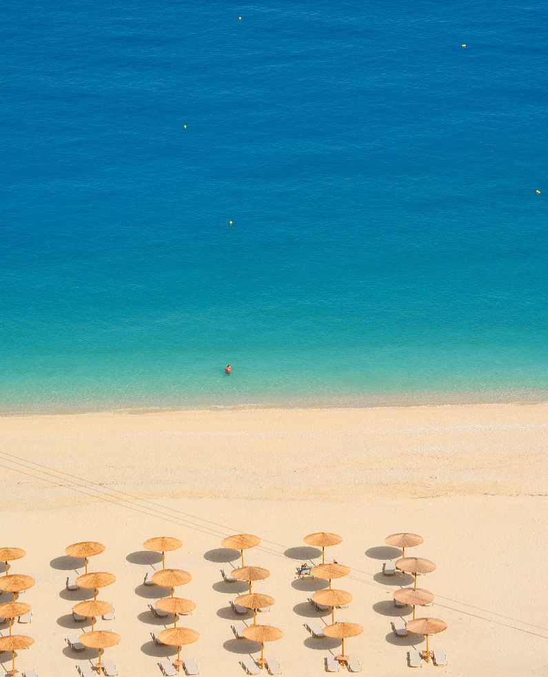 Myrtos sandy beach with rows of sun loungers and umbrellas