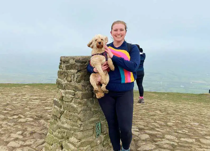 Mel posing at the stone summit of Mam Tor with her dog Lilly 