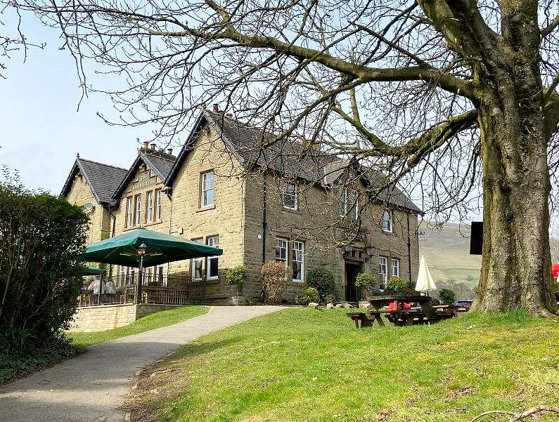 The Ramblers Inn in Edale, a stony old manor house with a large garden and leafless tree in front of it 