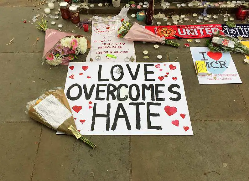 Love overcomes hate sign with flowers around a small memorial for the victims of the Manchester bombings