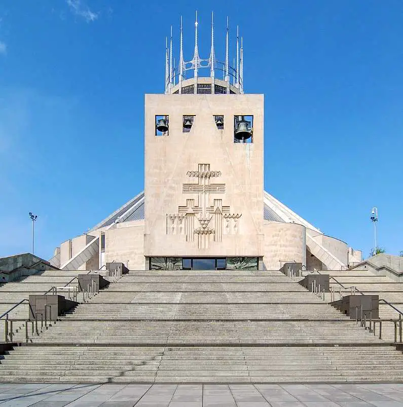 Outside Liverpool Metropolitan Cathedral, with a white stone squared front outside with bells and symbols of the cross