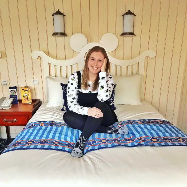 Mel sat on her white and blue bed at Disneyland Paris's Newport Bay Club Hotel
