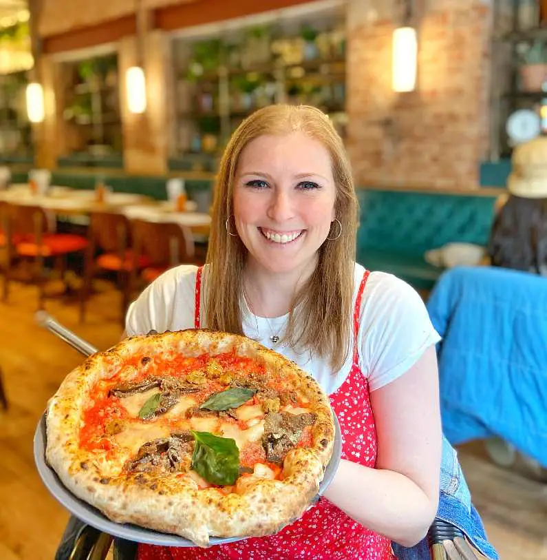 Mel holding up a pizza in Purezza Manchester