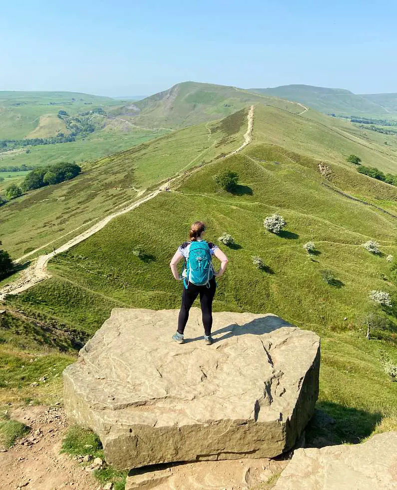 Mel standing on a large rock over looking Mam Tor and other peaks in the Peak District