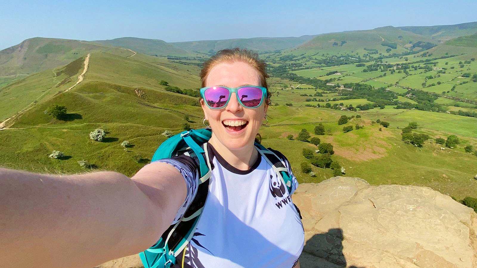 Mel smiling with the Mam Tor Circular peaks in the background from Back Tor in the Peak District on a sunny day