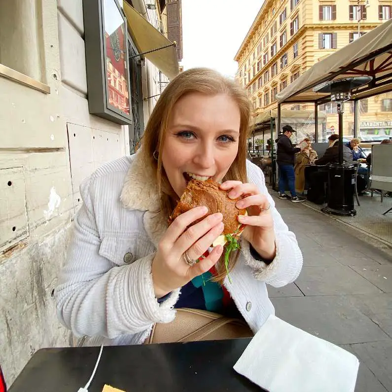 Mel sat outside 200 Gradi taking a bite of her deli sandwich 