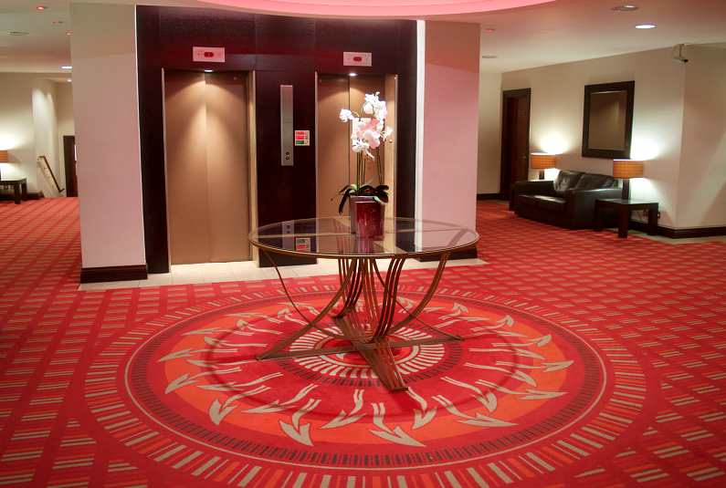 Reception of the Dragon Hotel in Swansea Bay with red dragon tail carpet and a glass table in the middle of the room