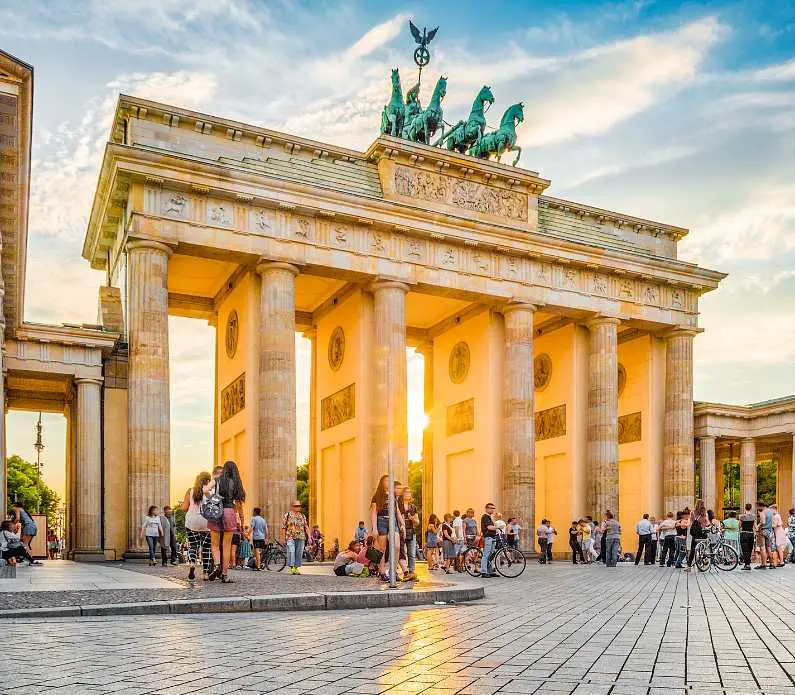 The Brandenburg Gate is an 18th-century neoclassical monument in Berlin with a green statue of four horses pulling a carriage on the top