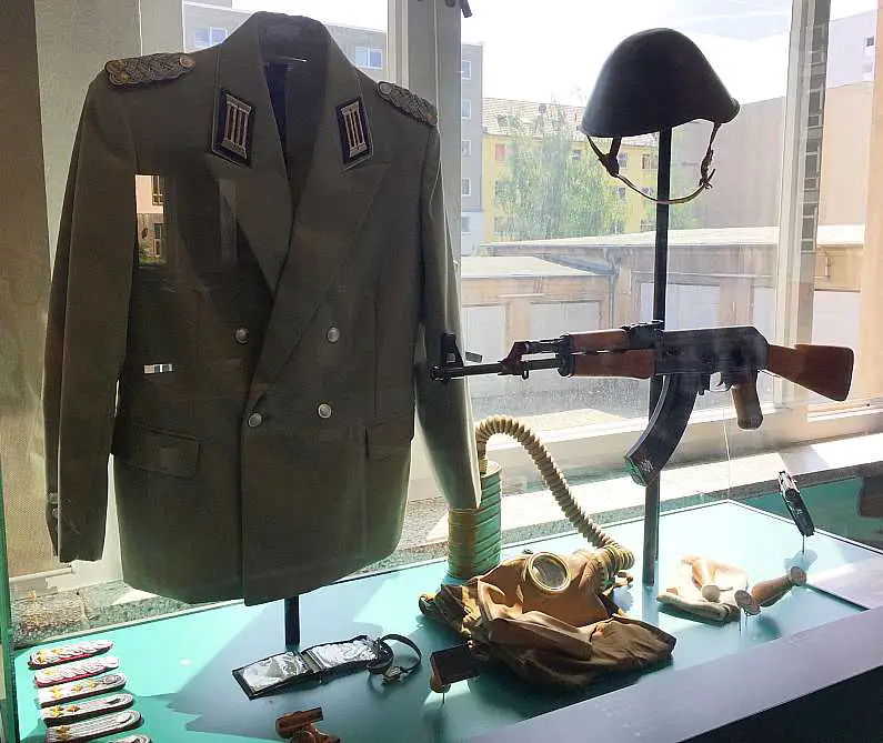 Post-war dark green officers uniform with a gun behind a glass case at the Stasi Museum in Berlin