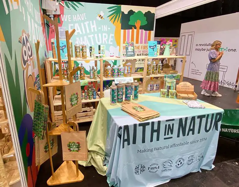 Faith in Nature stand with colourful cartoon nature banners in the background and wooden shelves that have rows of cleaning products