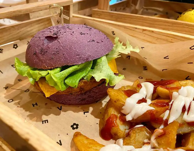 Purple cheese burger with chips covered in red and vegan mayo sauce