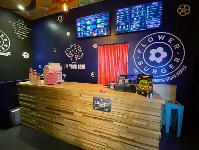 Front counter at Flower Burger with deep blue walls featuring the flower logo 