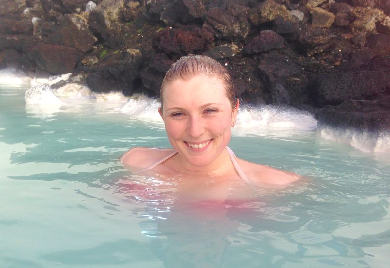 Mel smiling by some jagged rocks swimming in the Blue Lagoon
