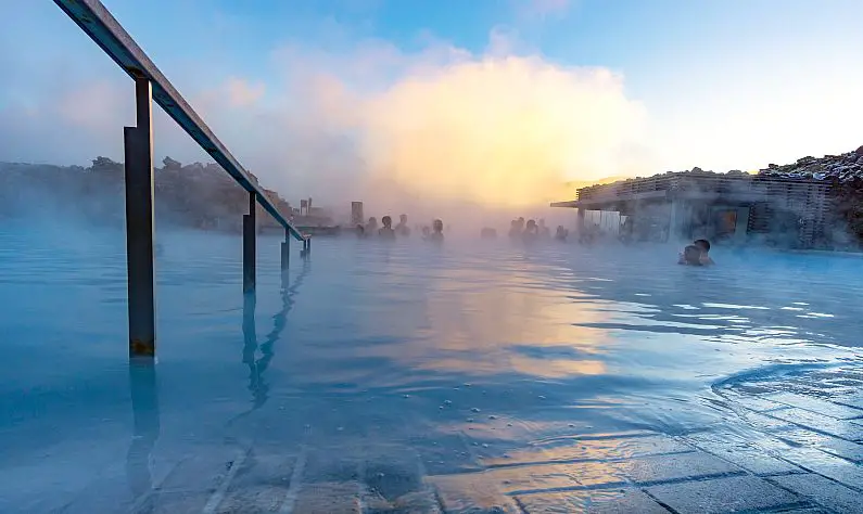 View of the Blue Lagoon from the entry steps with lots of mist in the background and people in the swimming in the background