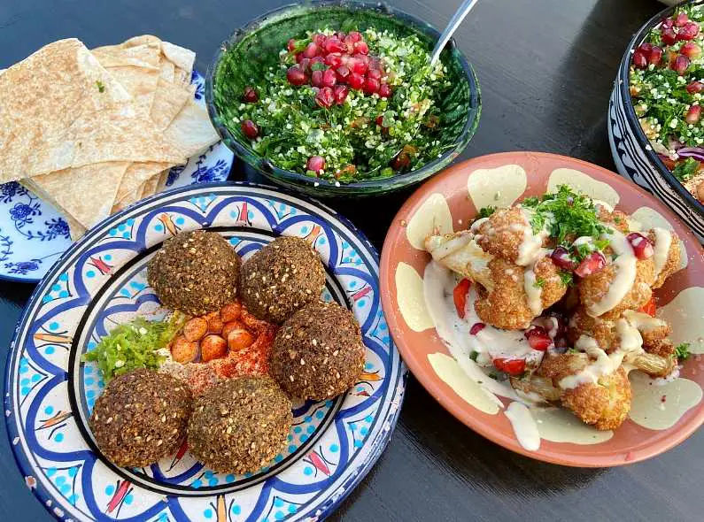 Colourful plates of Lebanese food with falafel, fried cauliflower, flat breads and tabbouleh