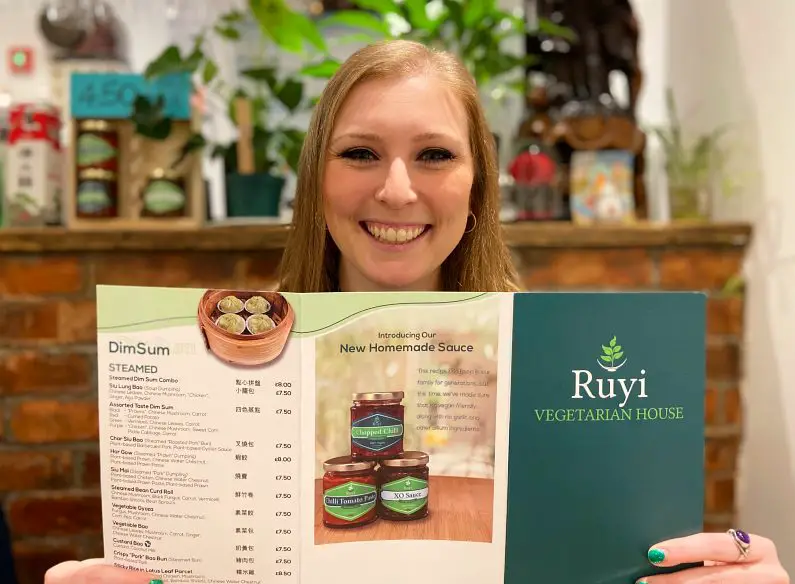 Mel holding up a Ruyi Vegetarian House menu in front of her and smiling