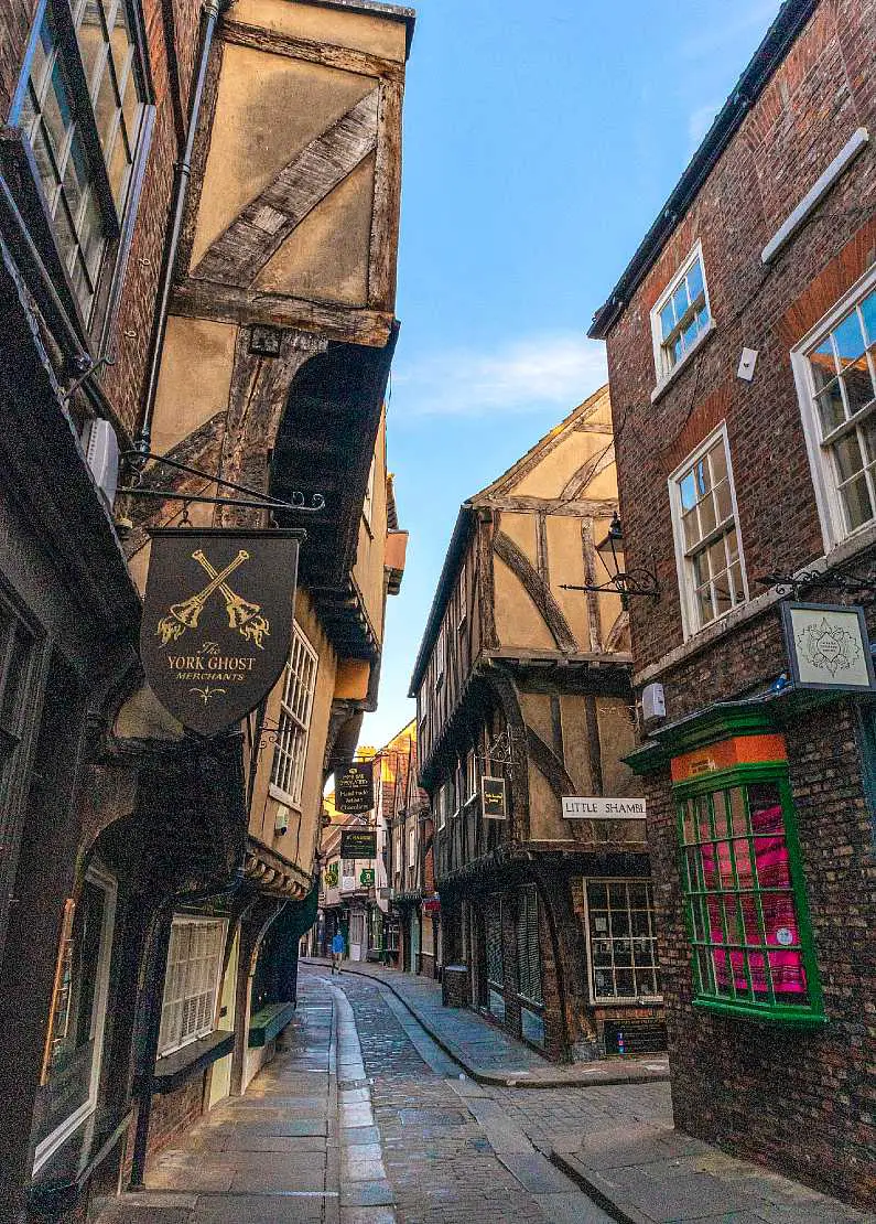Medieval main street in York, UK with brown facades, windows and signs which looks like Diagon Alley from the Harry Potter film series