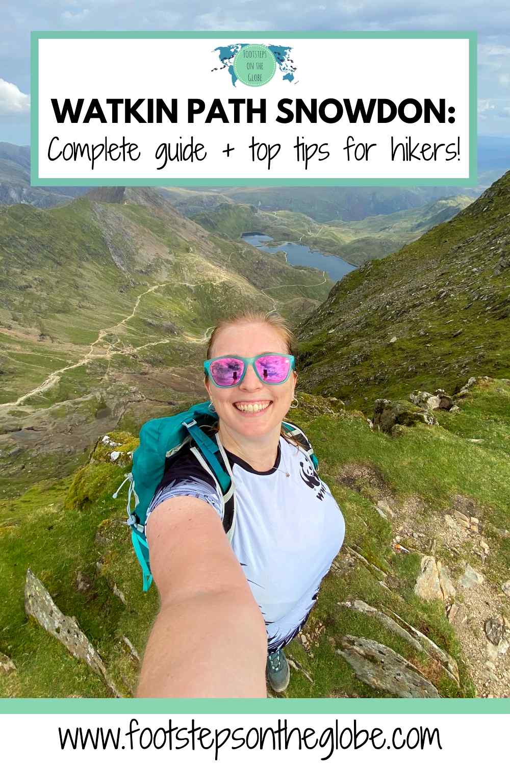 Pinterest image of Mel taking a selfie wearing a white t-shirt, green backpack and pink sunglasses with the green peaks and blue lakes of Snowdonia National Park in the background from the summit and the text: "Watkin Path Snowdon: Complete guide + top tips for hikers"