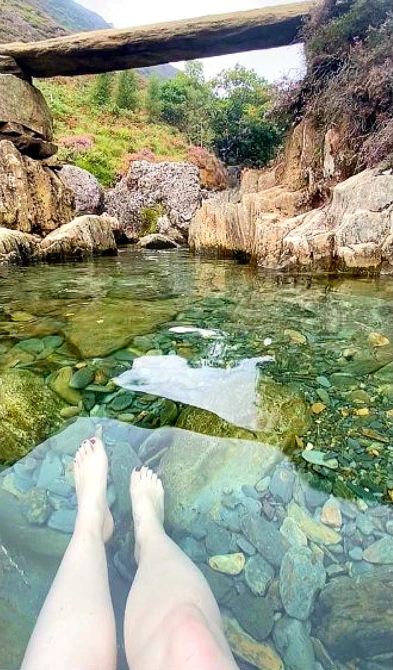 Mel's feet in the clear waters of the waterfall pool 