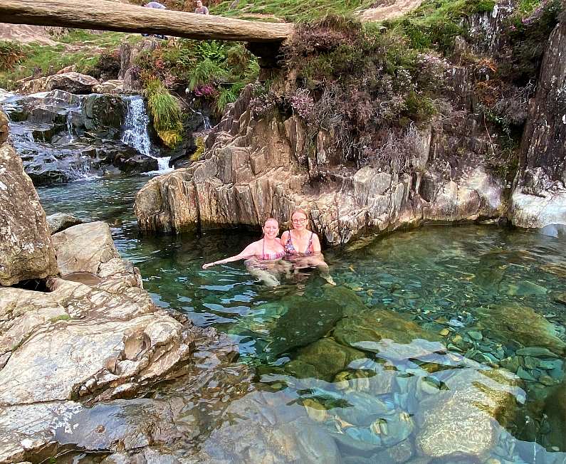 Two girls swimming in the Watkin Path Waterfall pool with the waterfall in the background 