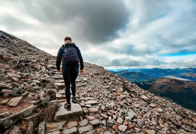 Female hiker heading to the summit of Ben Nevis near the top with valleys in the background
