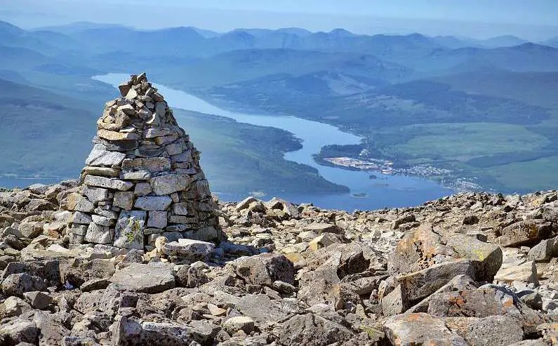 View of a valley with a river from the summit of Ben Nevis with a stone mound in the foreground